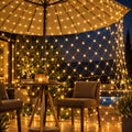 Filet lumineux doré installé sous un parasol, ambiance chaleureuse