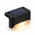 Lampe solaire noire fixée sur une clôture, lumière chaude allumée
